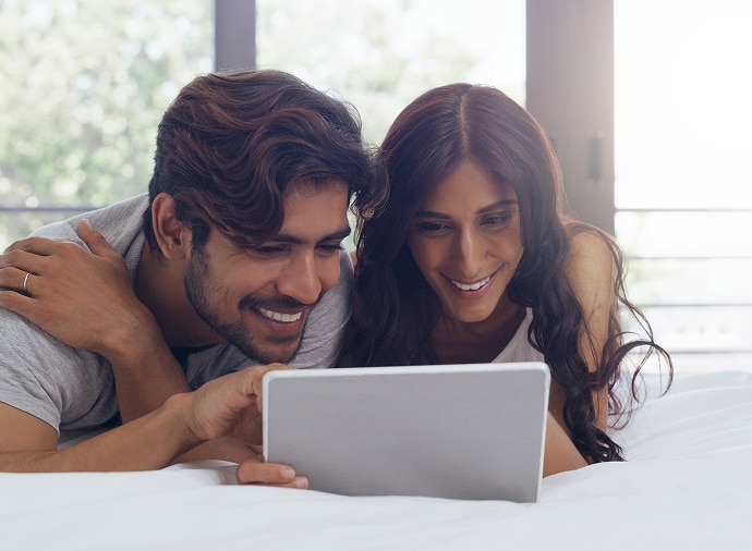 Hombre y mujer riendo mientras miran una tablet